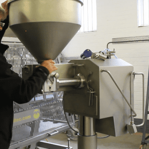 Operator manually dismantling a Volumetric Sauce Depositor (VSD) for cleaning or maintenance.